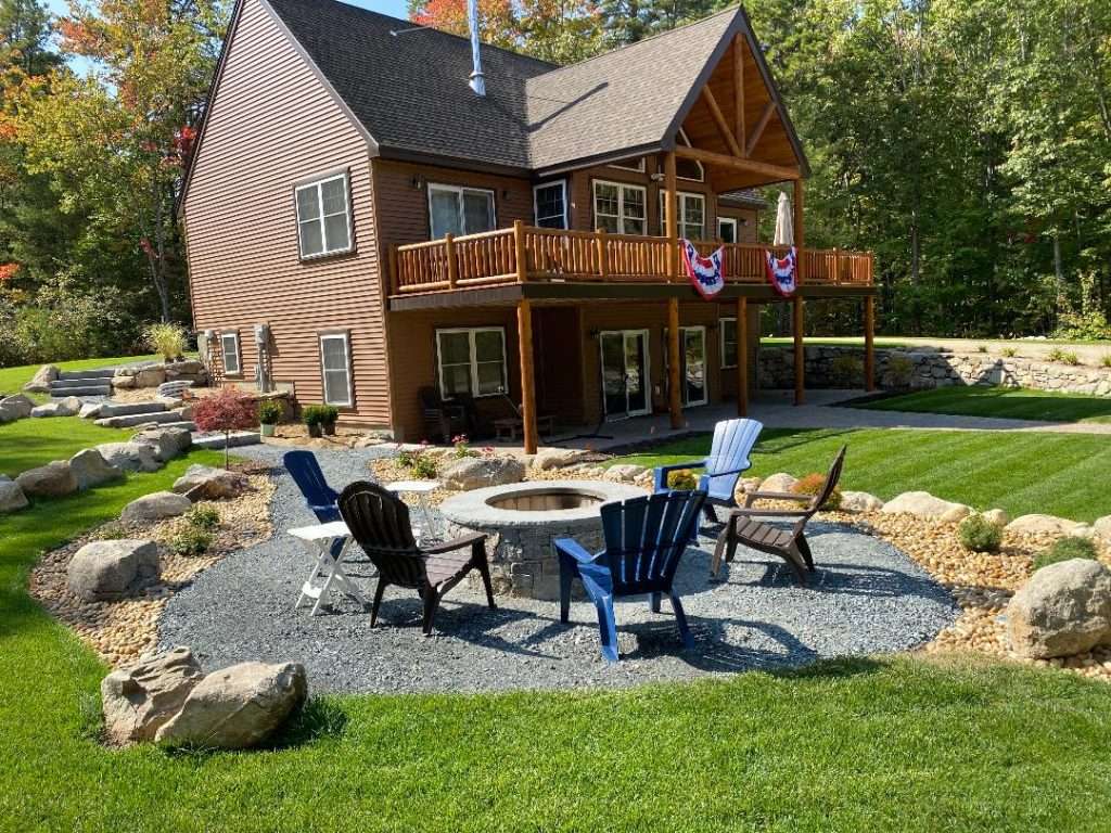 Completed stone and gravel fire pit installation with custom backyard landscaping by Landscapes by Tom in New Hampshire