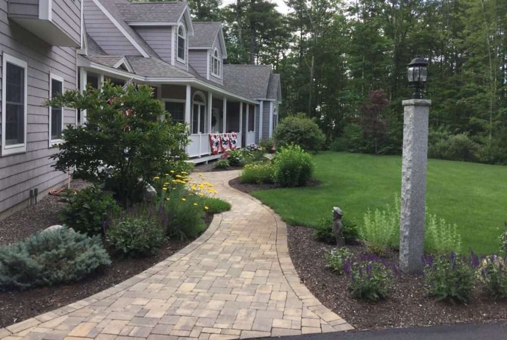 Completed entry walkway and planting bed landscape renovation with natural stone and shrubs by Landscapes by Tom in New Hampshire
