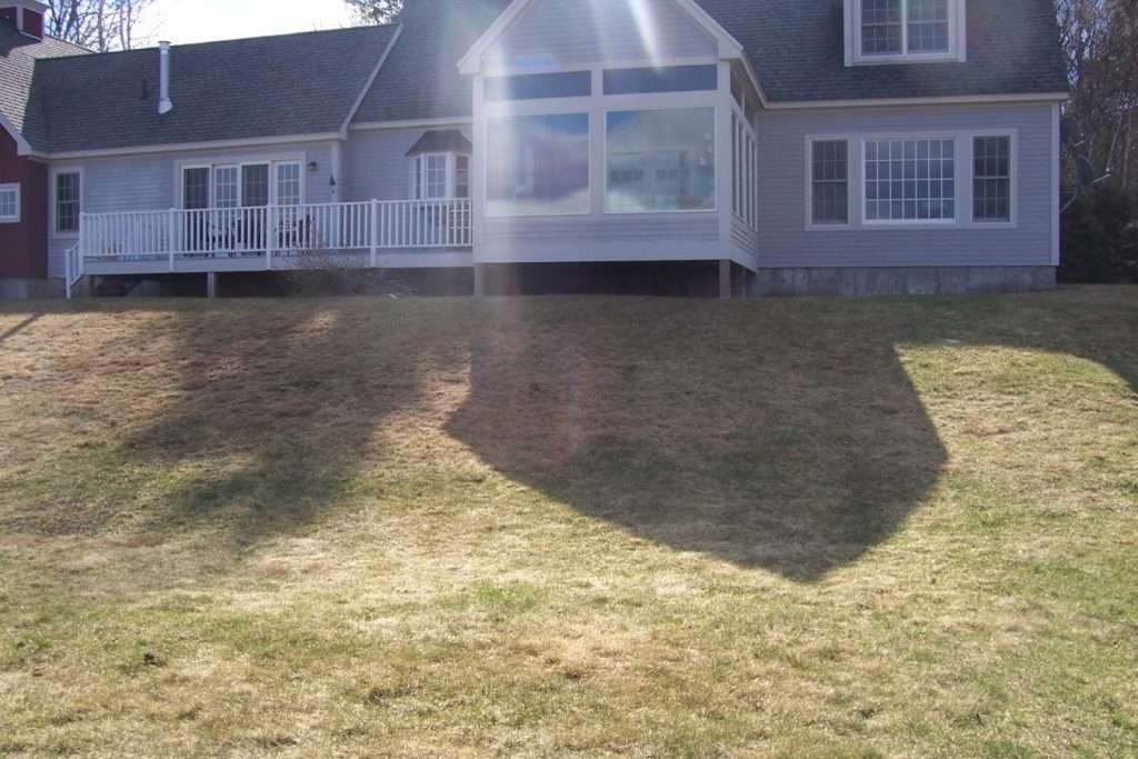 Before photo of a sloped backyard area prior to terrace patio and landscape installation by Landscapes by Tom in New Hampshire