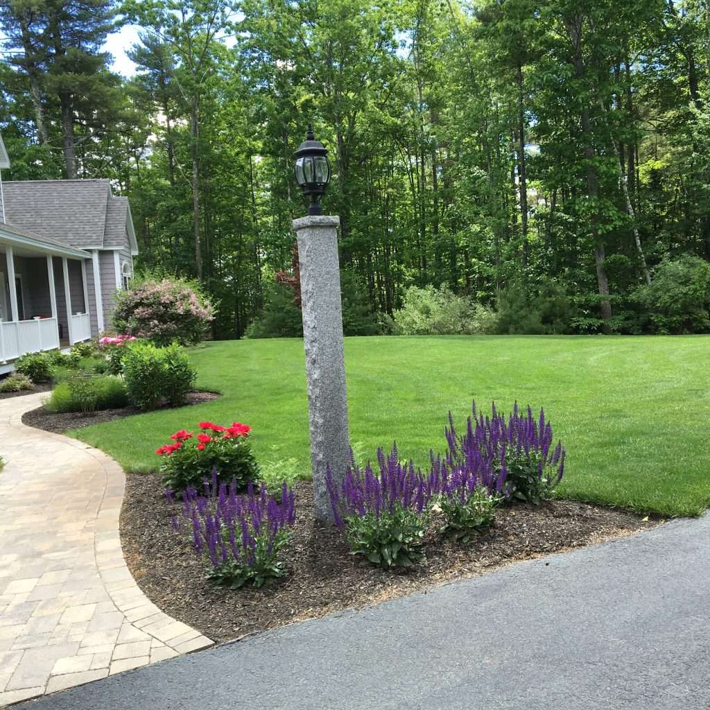 mulch bed flowers in bloom granite post