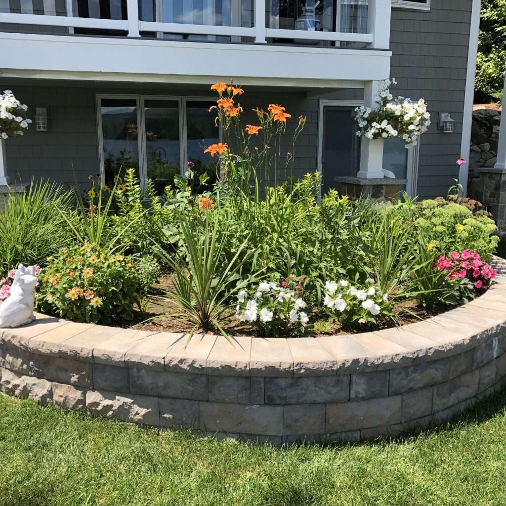 Raised stone garden bed with colorful perennial landscaping and waterfront home design by Landscapes by Tom in New Hampshire