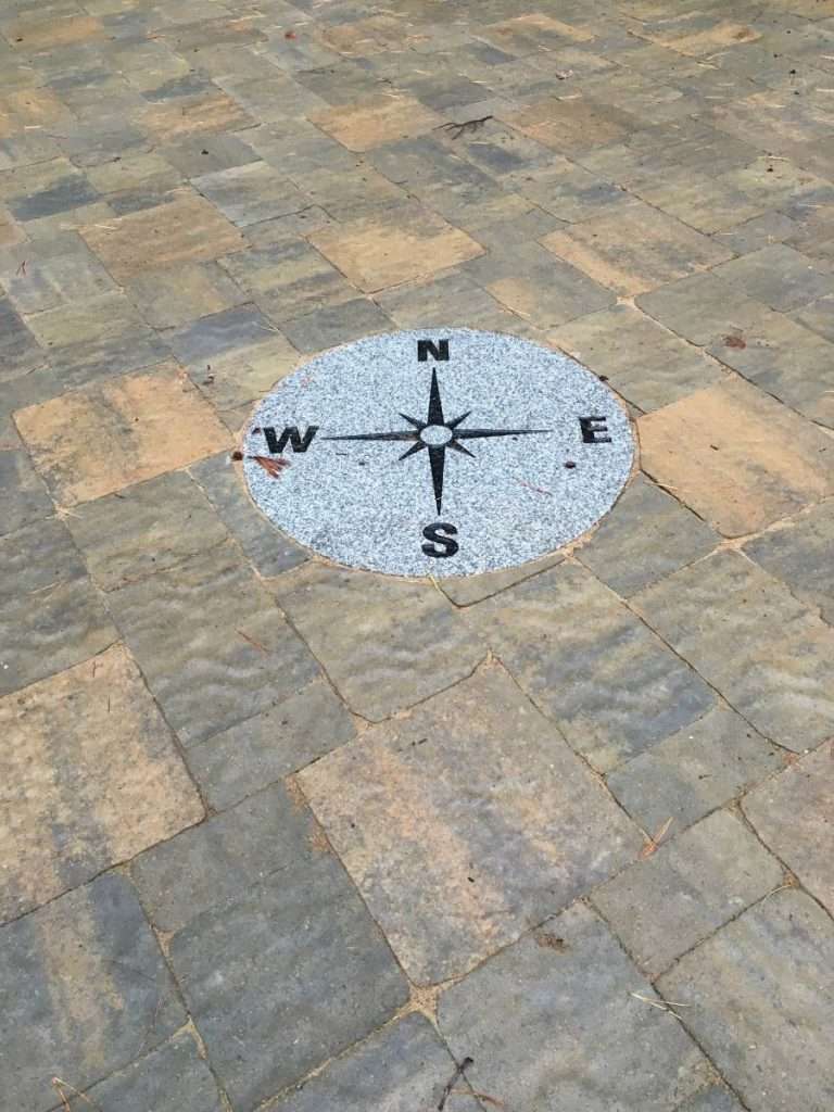 Custom paver patio with decorative compass rose inlay designed and installed by Landscapes by Tom in New Hampshire