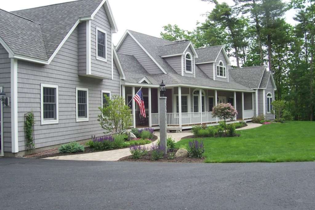 Front foundation landscaping with curved walkways, perennial gardens, and manicured lawn by Landscapes by Tom in New Hampshire